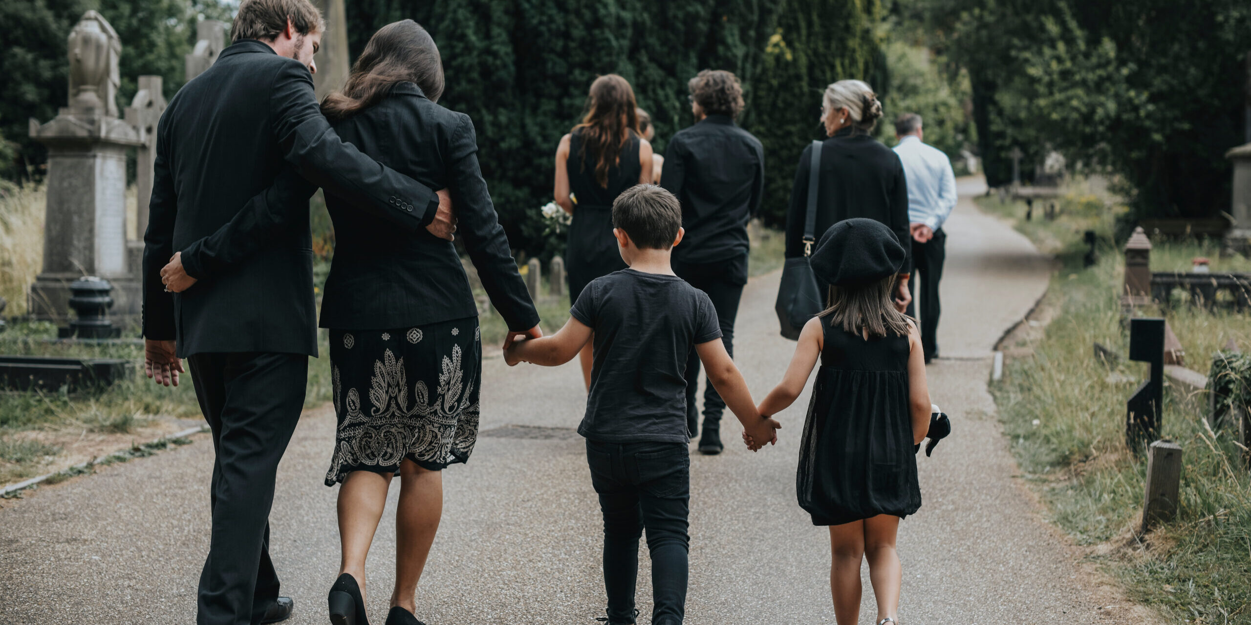 Grieving family walking through a cemetery Image from Webinar recording about adding bereavement to the national curriculum
