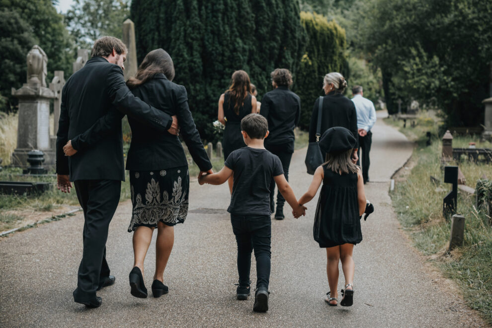 Grieving family walking through a cemetery Image from Webinar recording about adding bereavement to the national curriculum
